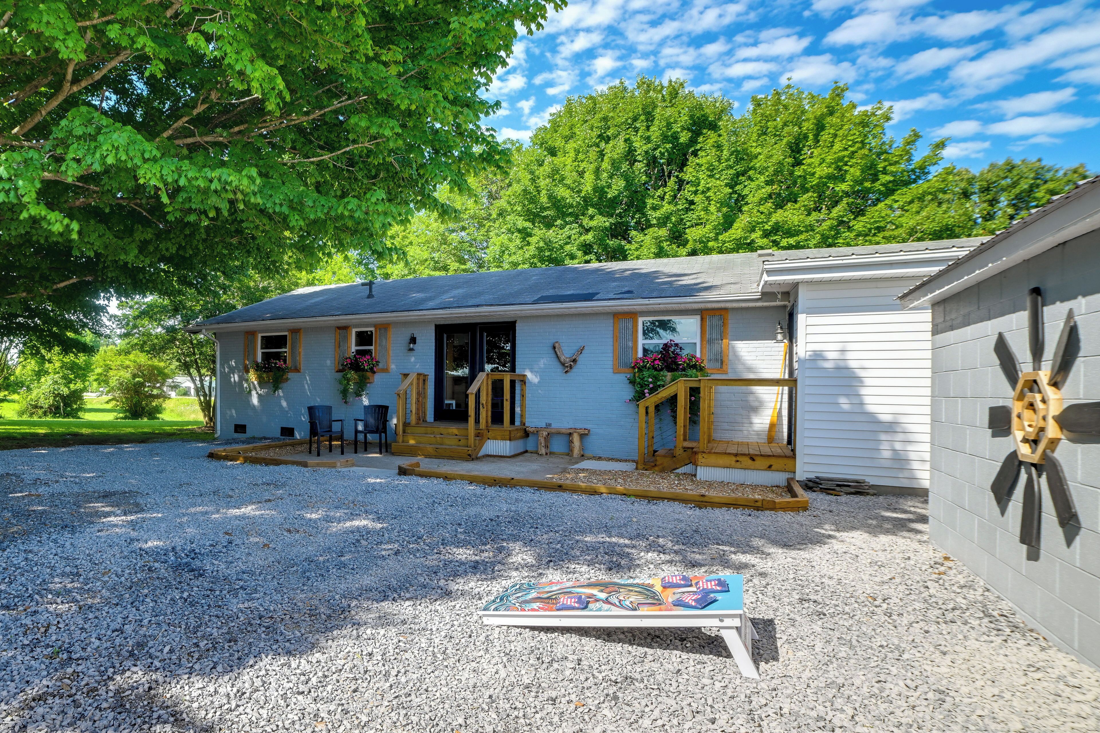 A single-story building with a porch, a gravel driveway, and a small outdoor seating area.