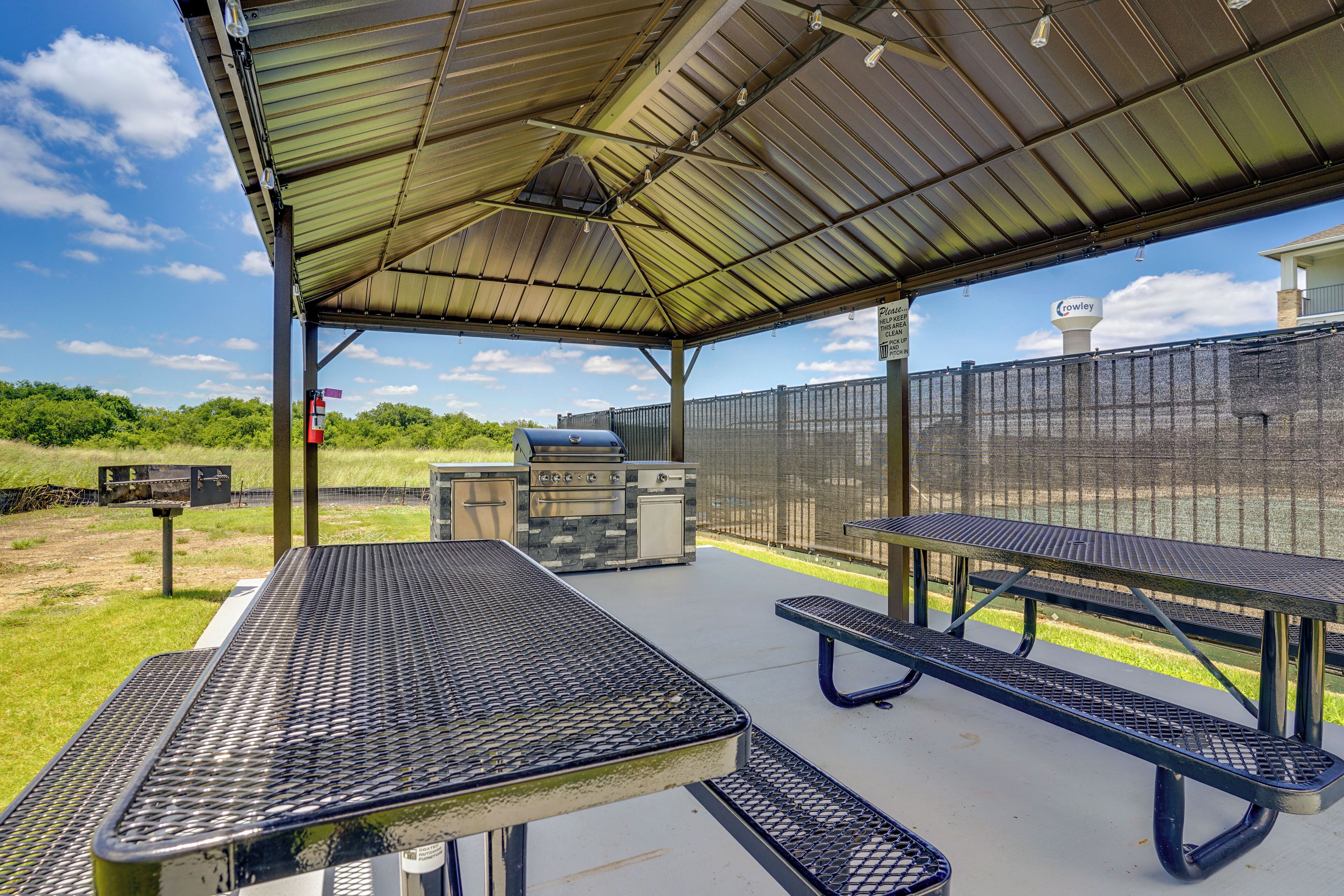 Une terrasse extérieure dotée d’un espace salon couvert, d’un barbecue et offrant une vue sur le paysage environnant.