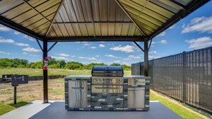 An outdoor barbecue area with a metal roof, stone accents, and a grill. - 2 Mi to Dtwn Crowley! Modern Escape w/ Pool Access (Crowley)