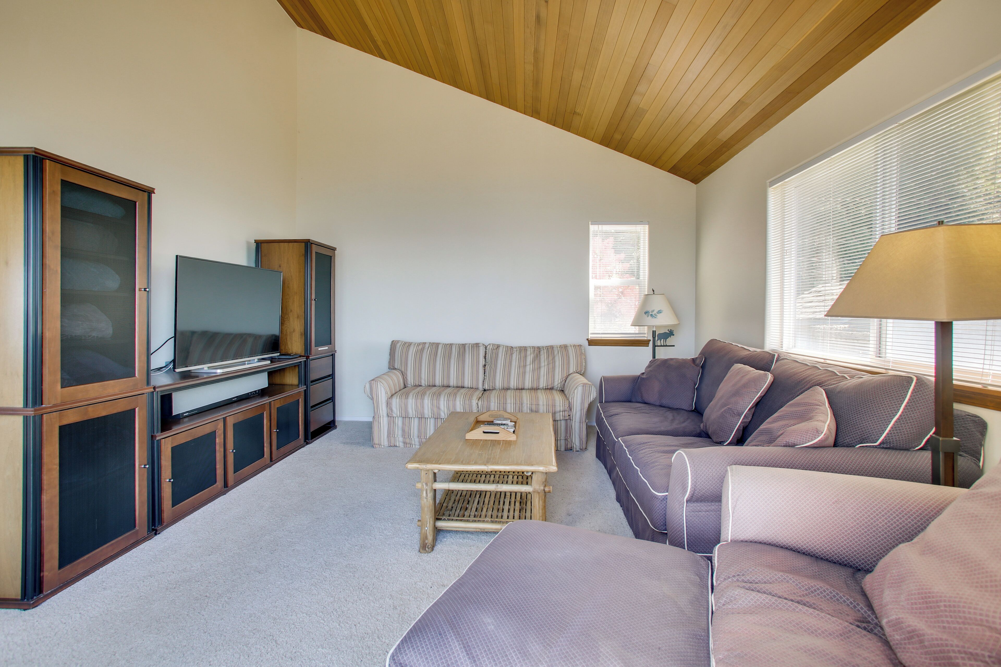 A living room with a television, sofas, a coffee table, and a lamp.