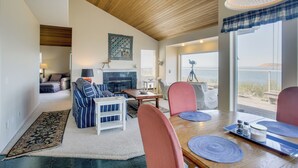 A spacious living room with a fireplace, a dining area with a table and chairs, and a view of the sea. - Direct Beach Access! Quiet Diamond Point Retreat (Sequim)