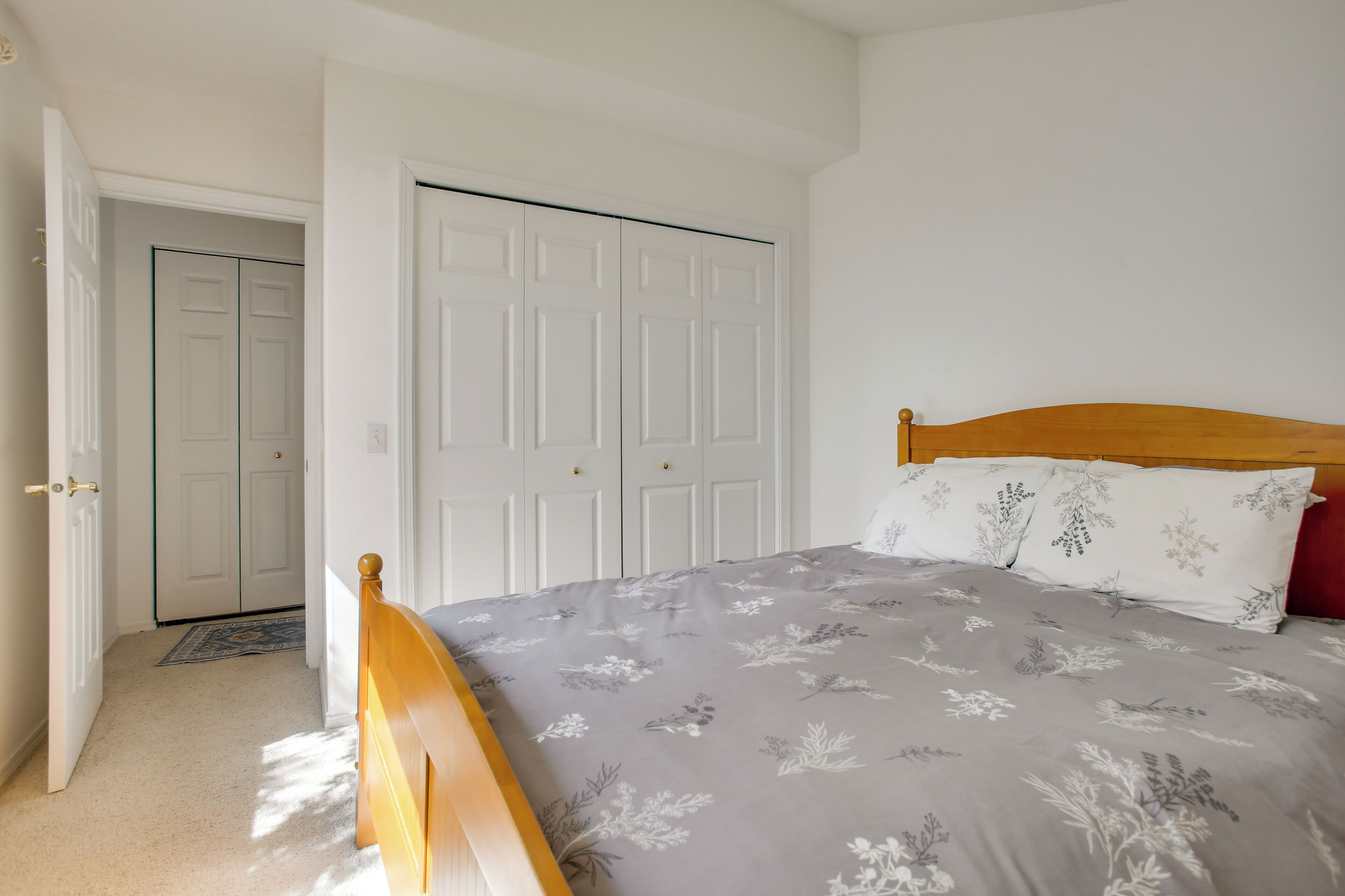 Un dormitorio con cama, armario y puerta que da a otra habitación.