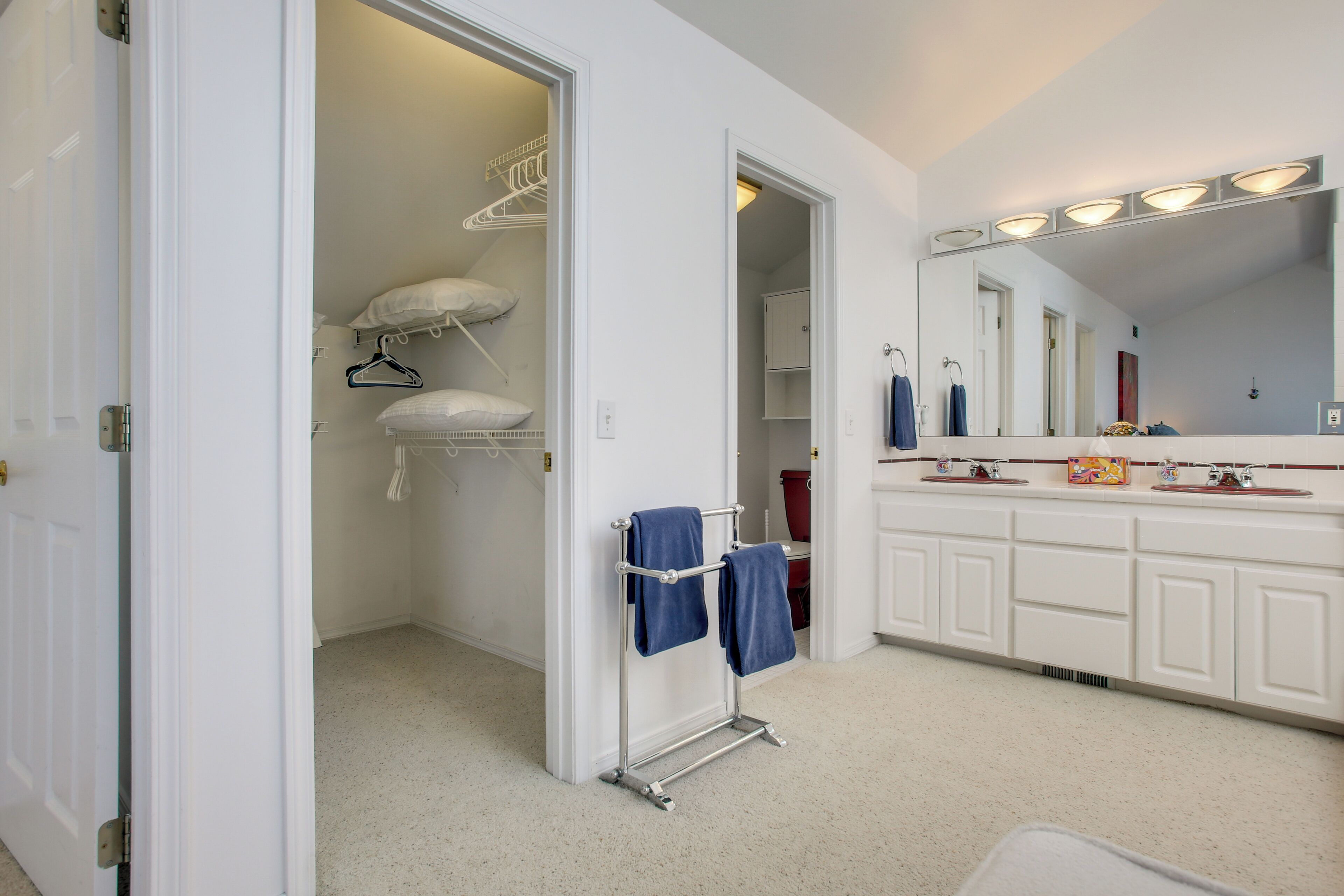 A bathroom with a white vanity, a large mirror, and a towel rack.