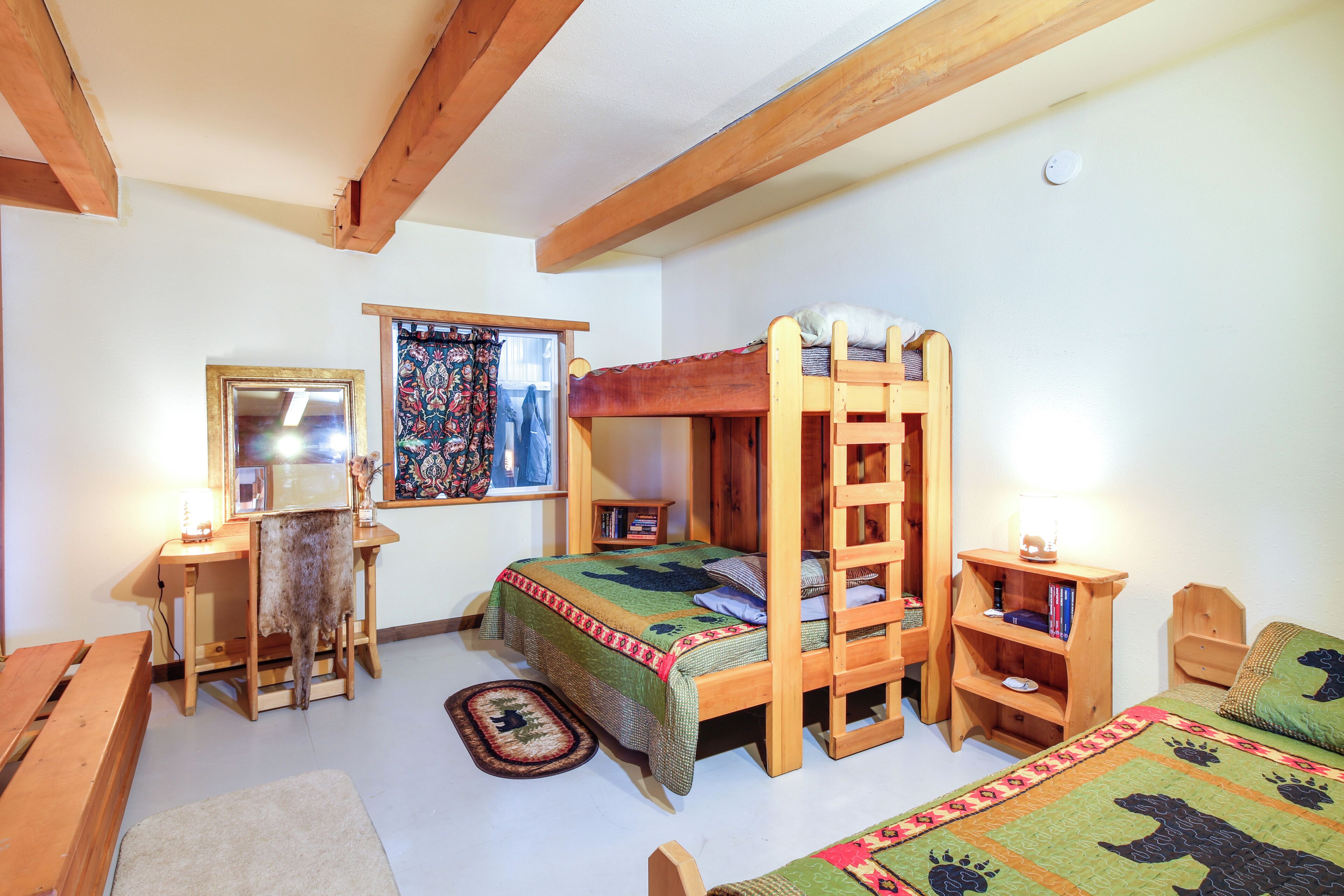 Une chambre avec un lit superposé, un bureau, une chaise et une petite bibliothèque.