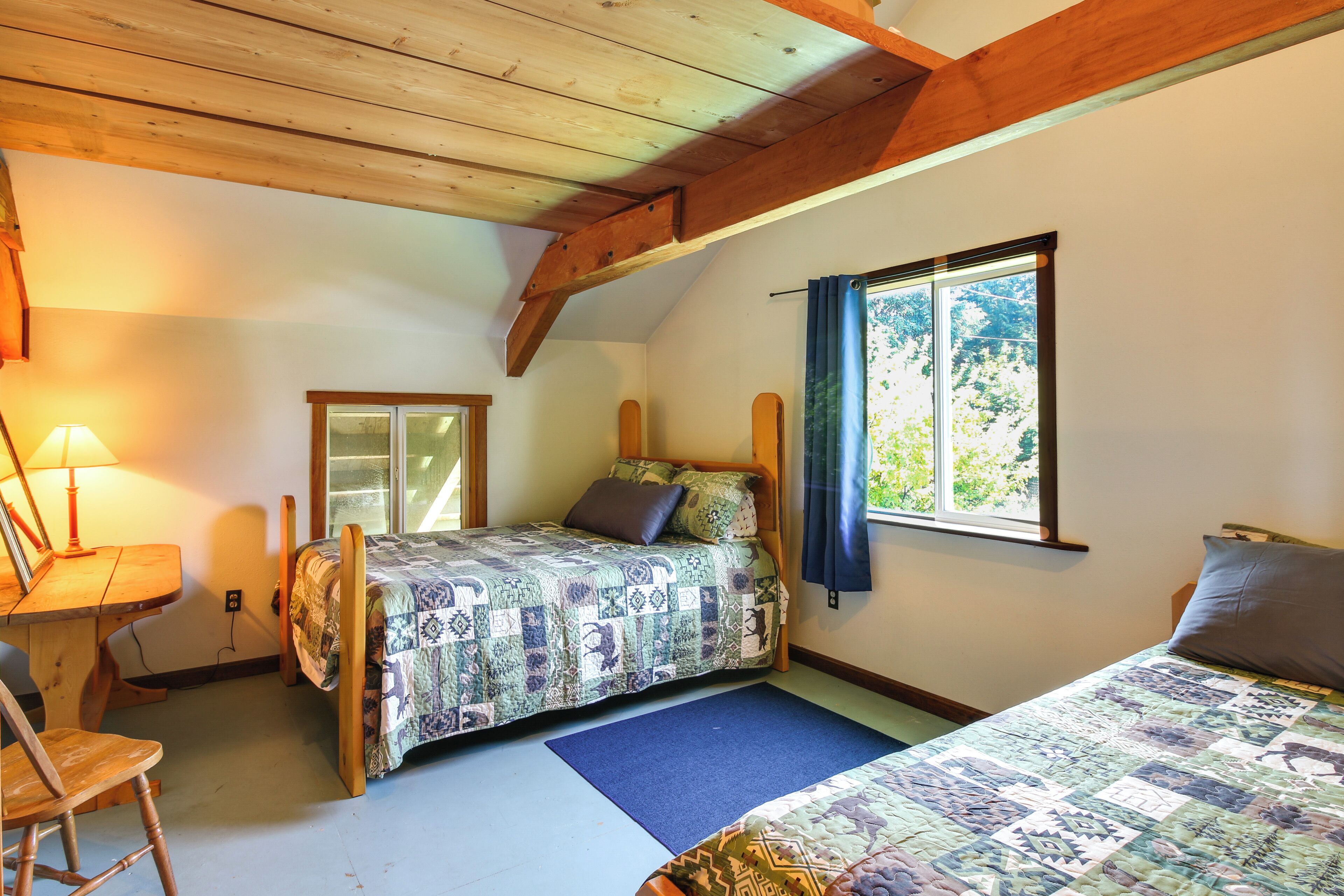 Un dormitorio con cama, una silla, un escritorio y una ventana con cortinas.