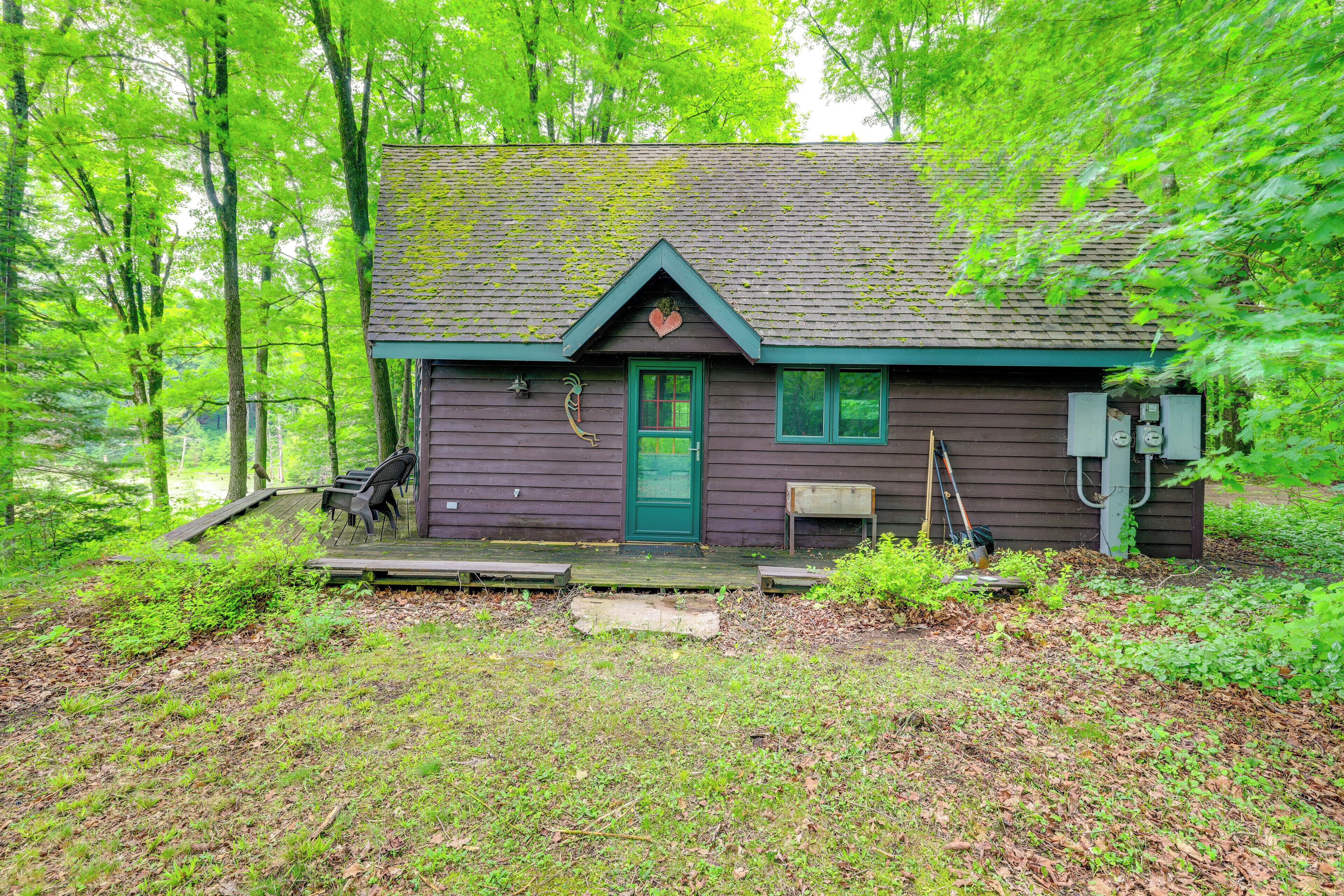 A cabin with a green door, a small porch, and a utility box.