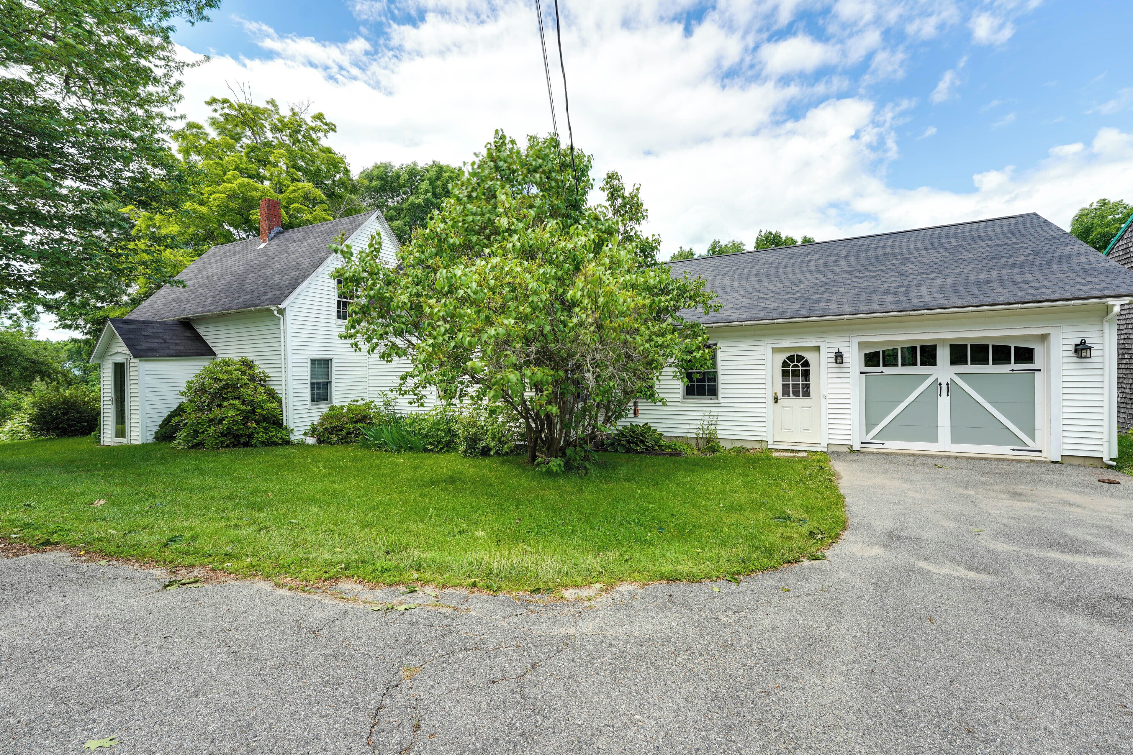 A single-story house with a garage, surrounded by a well-maintained lawn and trees.