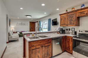 A modern kitchen with wooden cabinets, a dishwasher, an oven, and a built-in TV. - Hamilton Charm Place, 4 Bdrm, 2 Bath, Step-free (Hamilton)