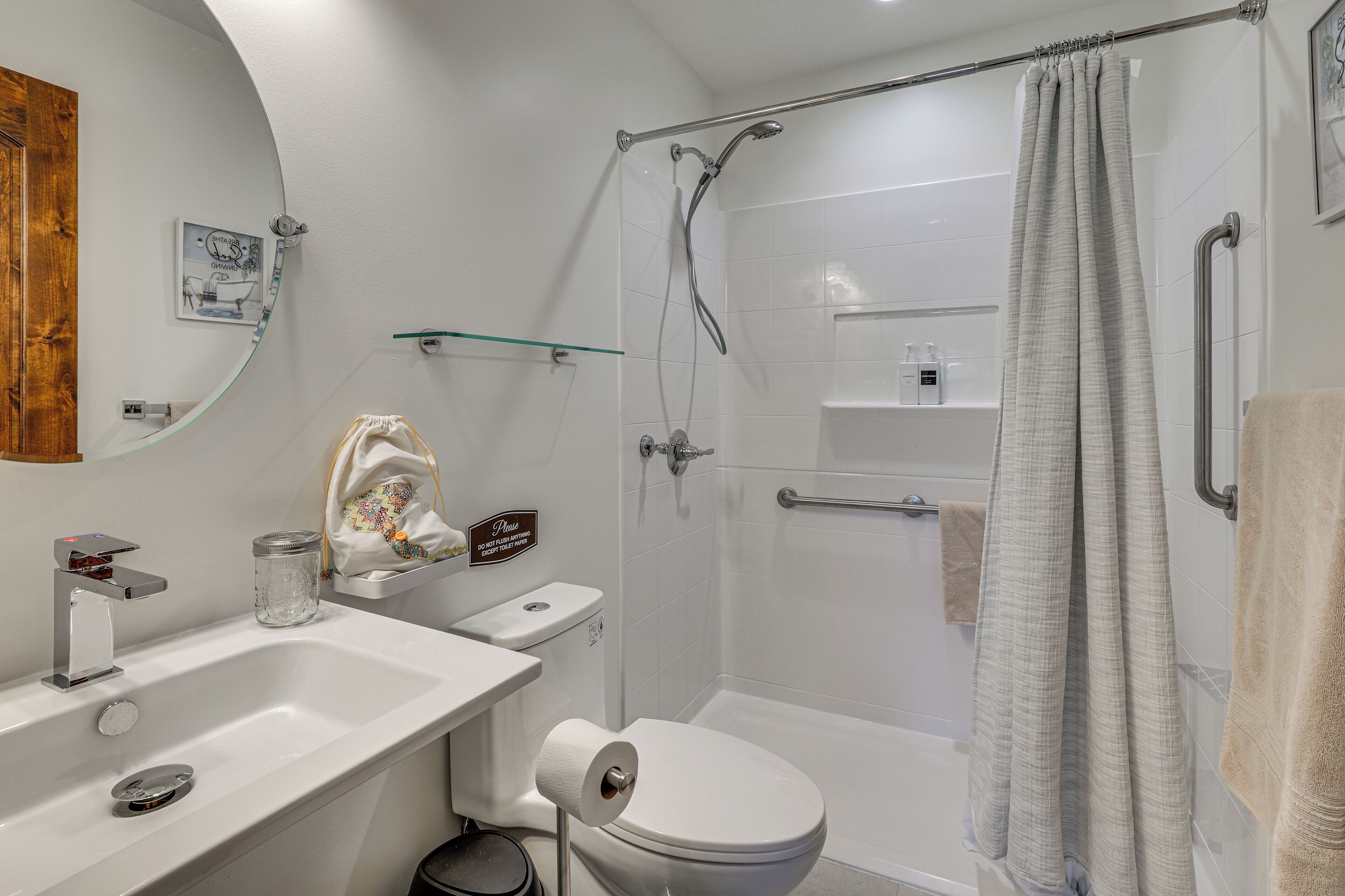 Une salle de bain moderne équipée d’une douche, de toilettes, d’un lavabo et d’une étagère en verre.