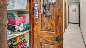 Una puerta de madera con manija, un letrero encima y un pasillo con suelo de baldosas.