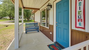 Un porche con una puerta azul, un banco y un felpudo.