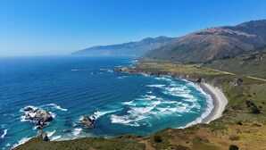 Paisatge costaner amb una platja, oceà i muntanyes.