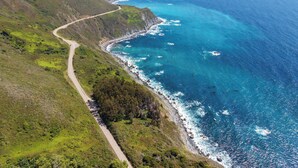 Una carretera costanera serpenteja per un paisatge verd amb vista a l'oceà.