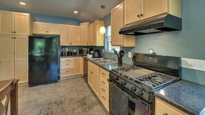 A modern kitchen with wooden cabinets, a black refrigerator, a stove, and a microwave.