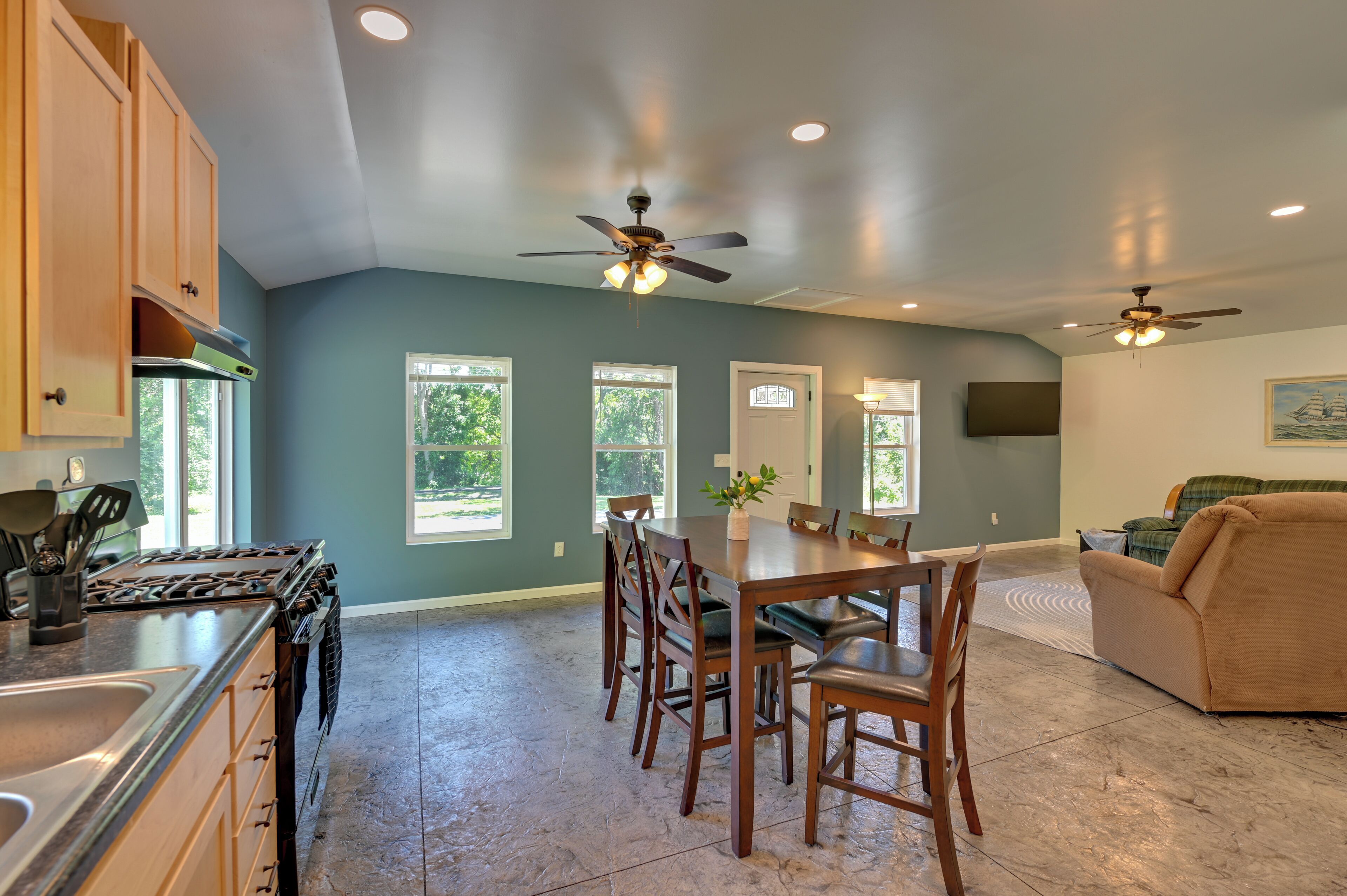 A kitchen with a stove, cabinets, and a dining area with chairs and a table.