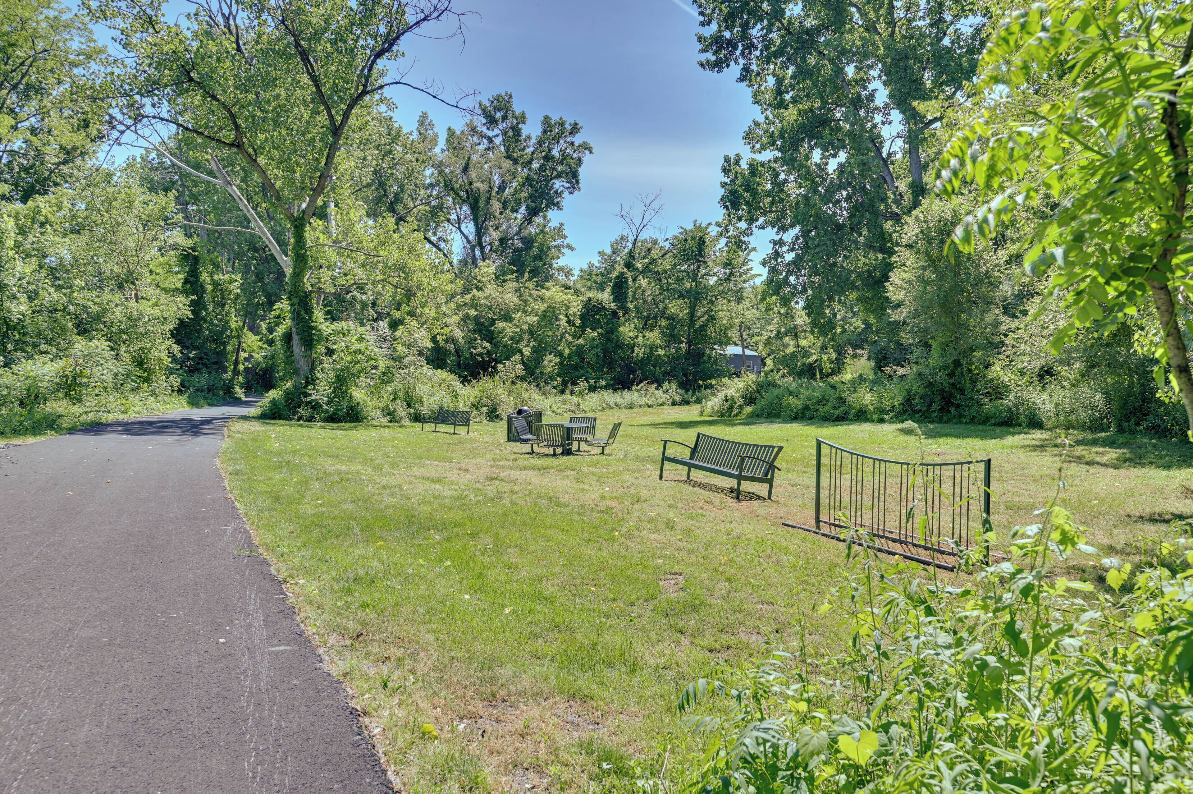 A park with a paved path, benches, and a fence.