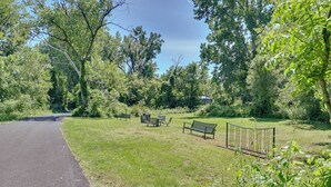 A park with a paved path, benches, and a fence.