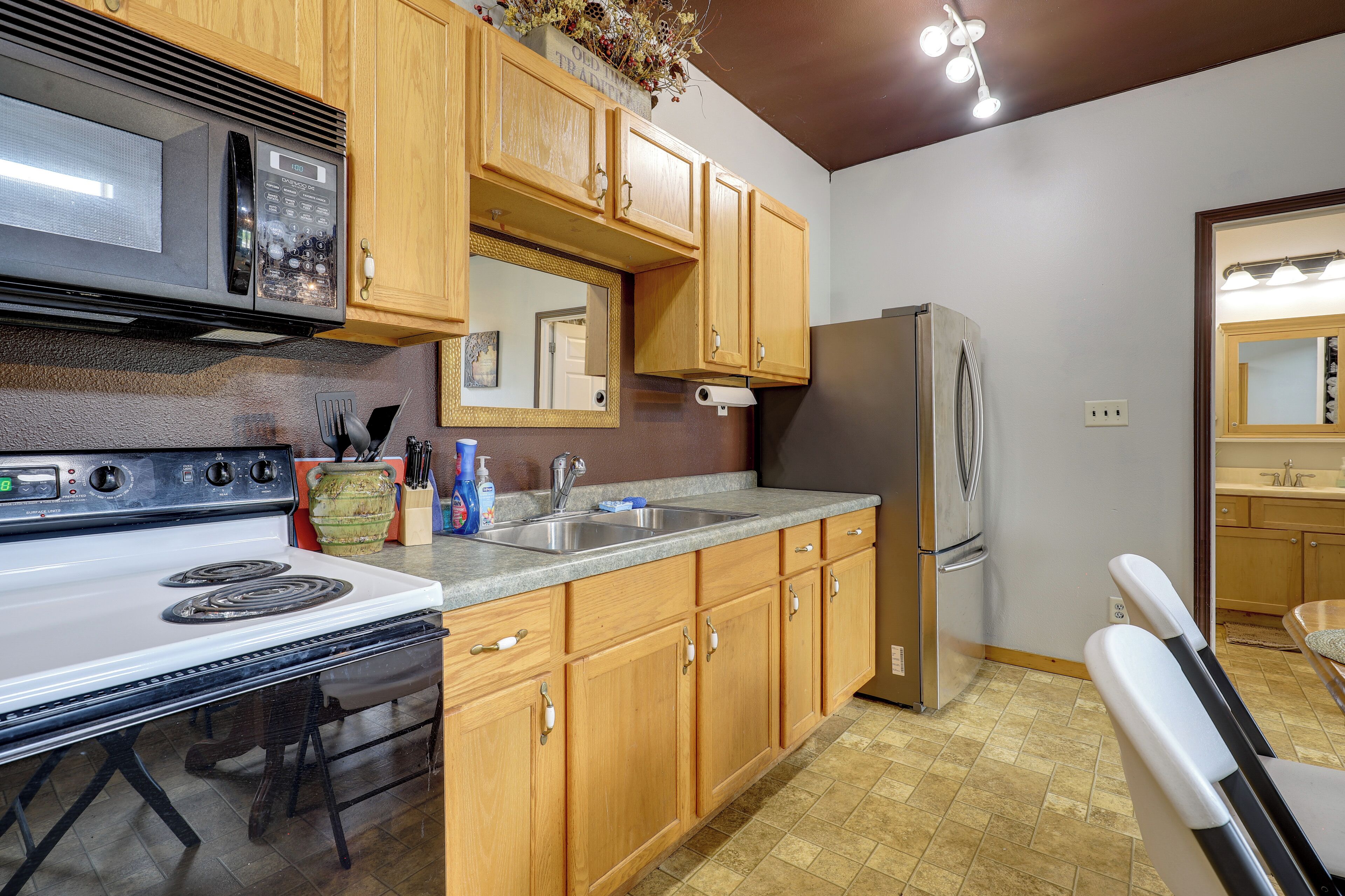 A kitchen with wooden cabinets, a stainless steel refrigerator, a microwave, and a stove.