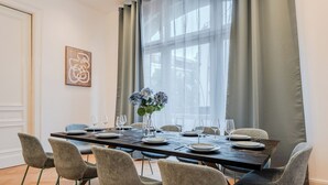 A dining area with a long table set for six, surrounded by six chairs, with a vase of flowers in the center. - Grand Living Apartment 150 m² 10 Guests 2 Bathrooms Ku'damm (Berlin)