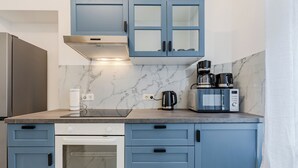 A kitchen with blue cabinets, a microwave, a coffee maker, and a stove. - Grand Living Apartment 150 m² 10 Guests 2 Bathrooms Ku'damm (Berlin)