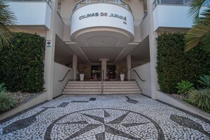 Ein Gebäudeeingang mit einem runden Schild, das 'Colinas de Juréia' zeigt, und einem gefliesten Bodenmuster.