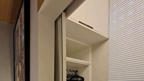 Un vestidor con perchero, estantes empotrados y una ventana con persianas.