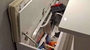 Una cocina con un cajón empotrado, una encimera blanca y un sofá beis en el fondo.