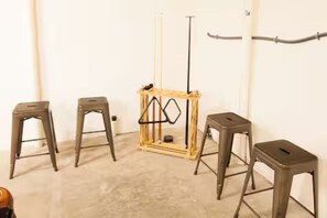 A room with four metal stools and a wooden structure with a pole.
