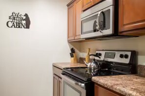 A kitchen with wooden cabinets, a stainless steel oven, and a microwave. - Charming Home / River Front / Hot Tub / Game Room (Sevierville)