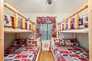A room with bunk beds, each with a patterned bedspread and pillows.