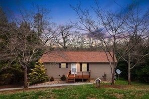 A single-story house with a front porch, a satellite dish, and a small yard. - Charming Home / River Front / Hot Tub / Game Room (Sevierville)