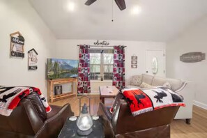 A living room with a fireplace, a coffee table, and a couch with a blanket. - Charming Home / River Front / Hot Tub / Game Room (Sevierville)