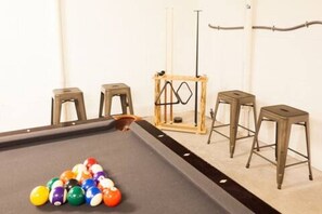 A pool table with a set of stools and a pool cue rack. - Charming Home / River Front / Hot Tub / Game Room (Sevierville)