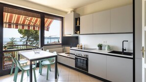 Une cuisine moderne dotée d’une grande fenêtre, d’un coin repas avec des chaises et d’une vue sur la mer.