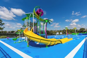 Ein Wasserpark mit einer gelben Rutsche, bunten Spielbereichen in Grün und Lila sowie einem blauen Poolbereich.