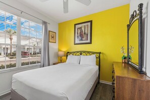 A hotel room with a bed, a bedside table, a mirror, and a window with blinds. - Private Pool*Resort Amenties*Close to Theme Parks! (Kissimmee)