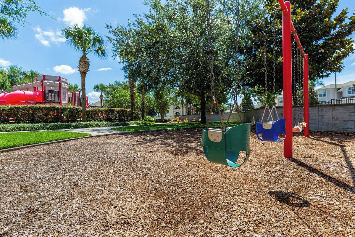 Ein Spielplatz mit Schaukeln und einer roten Rutsche.