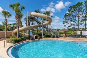 A swimming pool with a water slide, surrounded by palm trees and a clear sky. - Private Pool*Resort Amenties*Close to Theme Parks! (Kissimmee)