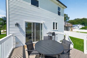 Ein Haus mit Terrasse, Grill und einer Glastür.