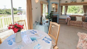 A room with a dining table, a sofa, and a fireplace. - Mor a Mynydd (Pwllheli)