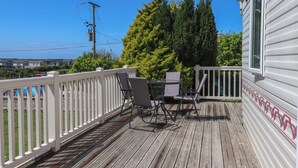 A wooden deck with a white railing, a table, and two chairs. - Mor a Mynydd (Pwllheli)