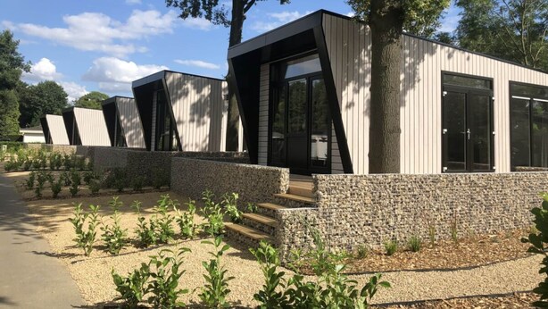En modern byggnad med en unik arkitektonisk design, bestående av en rad sammanlänkade strukturer med stora fönster och en grund av sten.