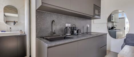 A modern kitchen with a built-in microwave, stainless steel sink, and a coffee maker.