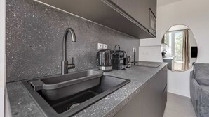 A modern kitchen with a granite countertop, stainless steel sink, and a coffee maker. - Modern Studio 3P - Aubervilliers (Aubervilliers)