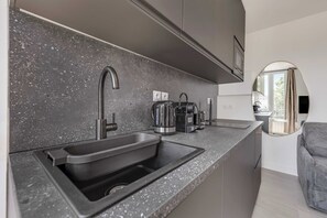 Una cocina moderna con encimera de granito, lavaplatos de acero inoxidable y cafetera.
