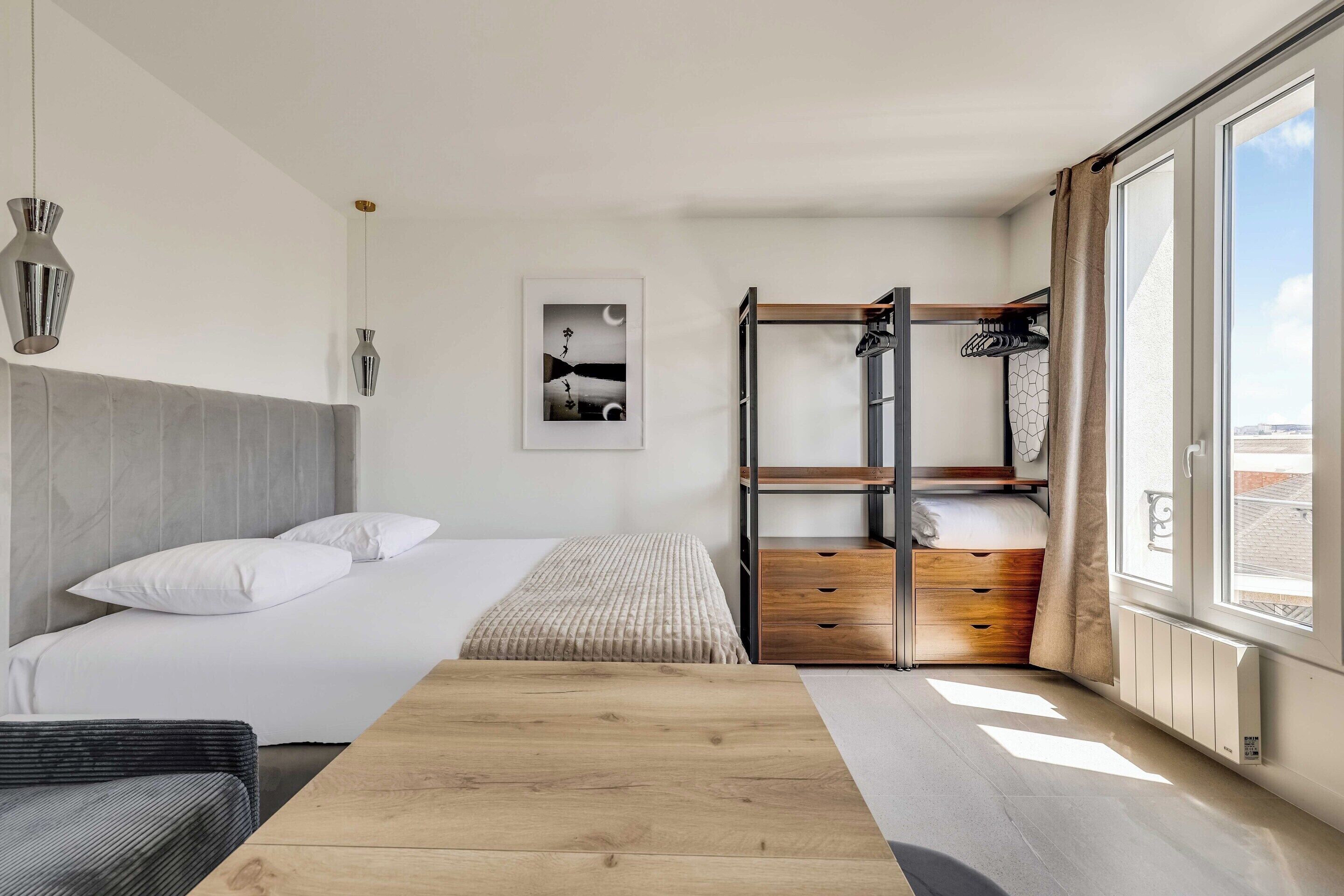 Un dormitorio moderno con una cama litera, una mesa de madera y un ventanal grande.