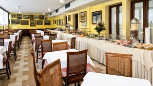 Un comedor con mesas y sillas, una barra de buffet y obras de arte enmarcadas en las paredes.