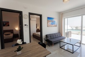 Un salon moderne avec un canapé, une table à manger agrémentée d’une plante et une grande fenêtre donnant sur la ville.