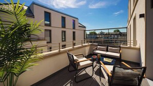 A rooftop terrace with a seating area, a small table, and a potted plant.