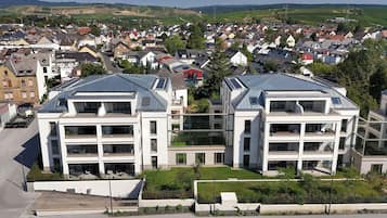 A modern residential building with multiple floors, large windows, and a flat roof with solar panels.